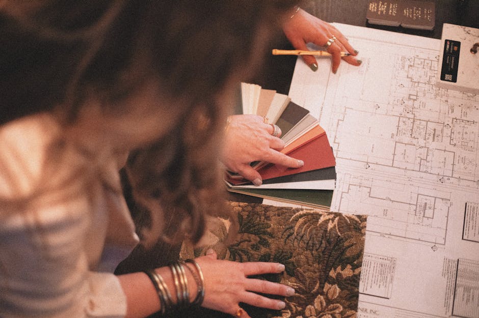 Designer consulting blueprints with fabric and color samples for interior project.